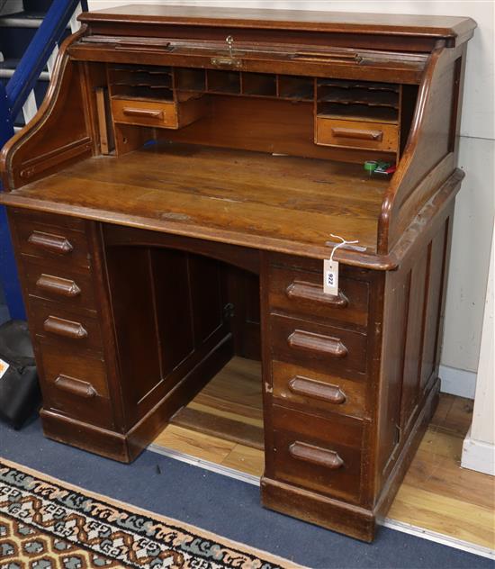 A 1920s oak five drawer tambour roll top desk W.106cm